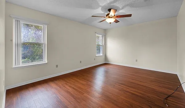 a view of a room with wooden floor and a ceiling fan