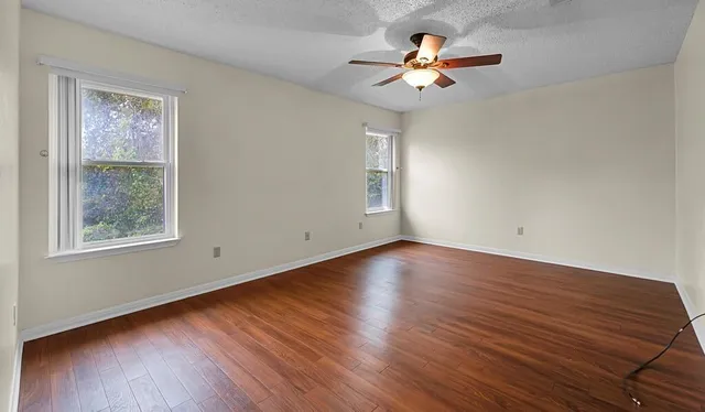 a view of a room with wooden floor and a ceiling fan