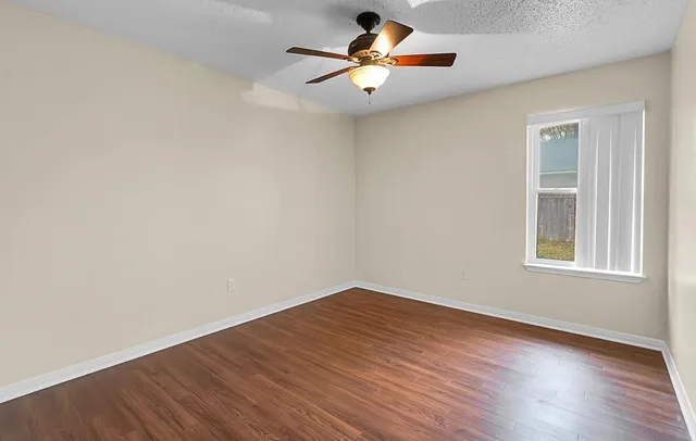 an empty room with wooden floor and windows