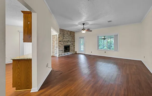 an empty room with wooden floor chandelier and windows