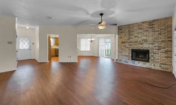 an empty room with wooden floor fireplace and windows