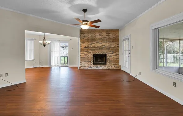 an empty room with wooden floor fireplace and windows