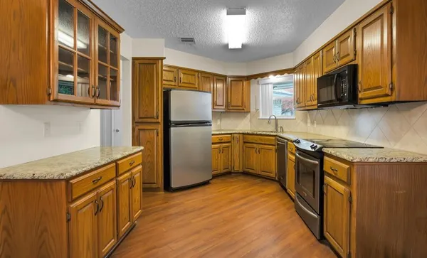 a kitchen with stainless steel appliances granite countertop a refrigerator a stove top oven a sink and dishwasher