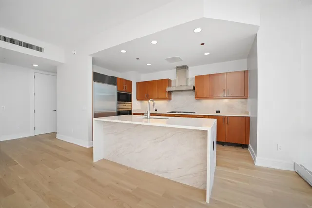 a large kitchen with stainless steel appliances kitchen island granite countertop a refrigerator and a sink