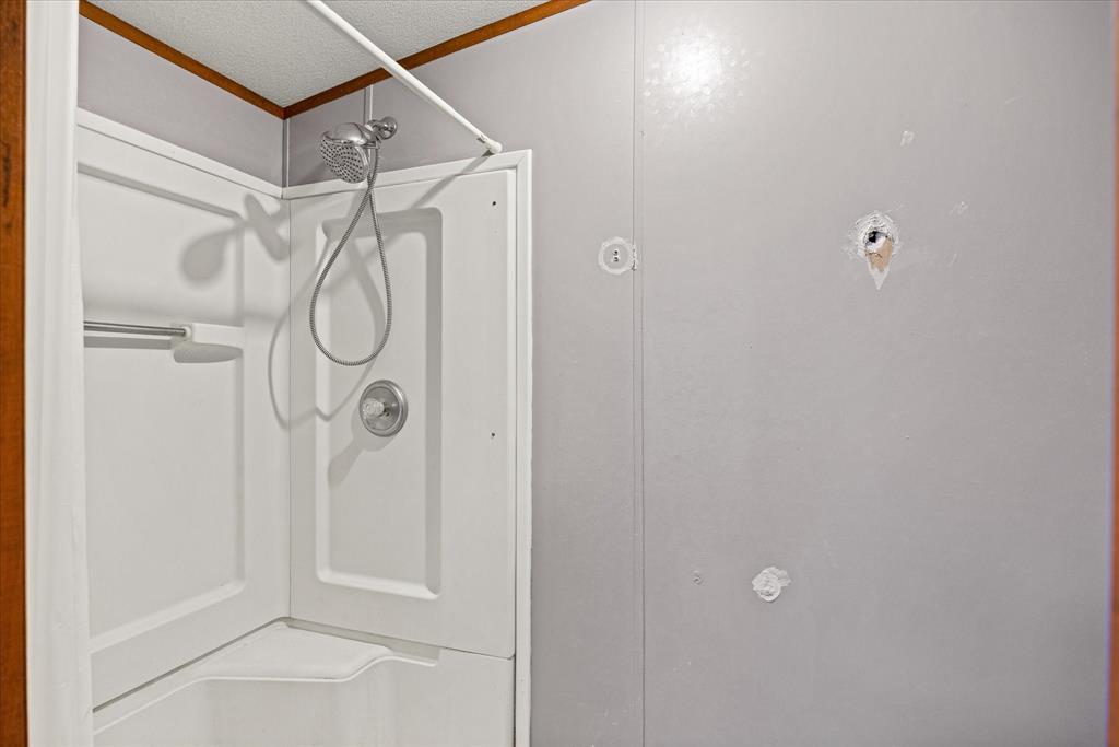 2903 Centaurus Way Granbury, TX 76048 - Photo 27 of 31 Bathroom view of a shower, a textured ceiling, and ornamental molding