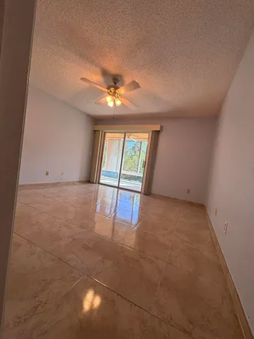 an empty room with windows and chandelier fan