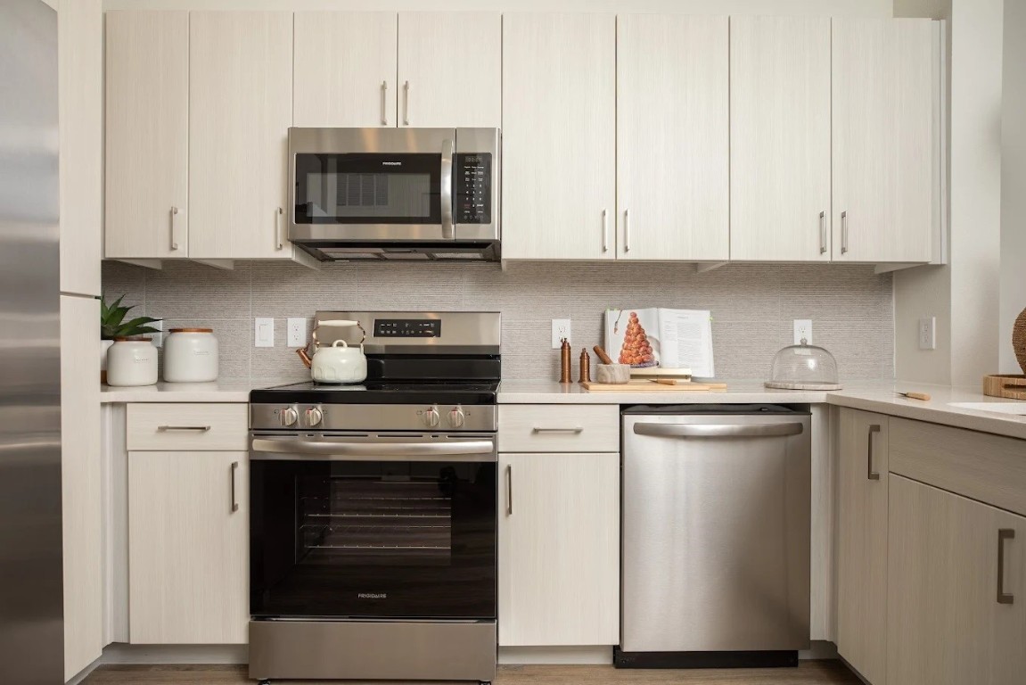 1690 North Loop, Unit 485 Houston, TX 77009 - Photo 5 of 28 a kitchen with stainless steel appliances granite countertop a stove a microwave and a white cabinets