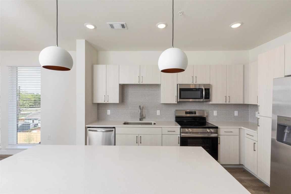 1690 North Loop, Unit 485 Houston, TX 77009 - Photo 8 of 28 a kitchen with stainless steel appliances a stove a sink a microwave a refrigerator and white cabinets with wooden floor