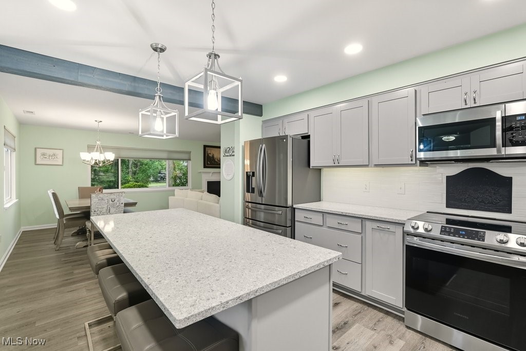 6753 Mill Road Brecksville, OH 44141 - Photo 8 of 34 Kitchen with appliances with stainless steel finishes, gray cabinetry, decorative backsplash, decorative light fixtures, and a breakfast bar