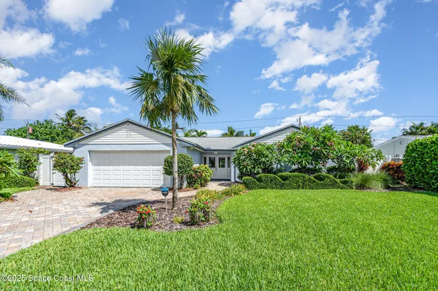 a front view of a house with a yard and potted plants