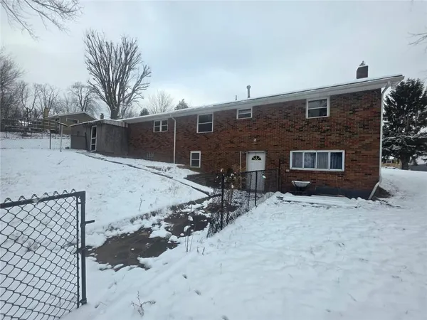 a front view of a house with a yard covered with snow