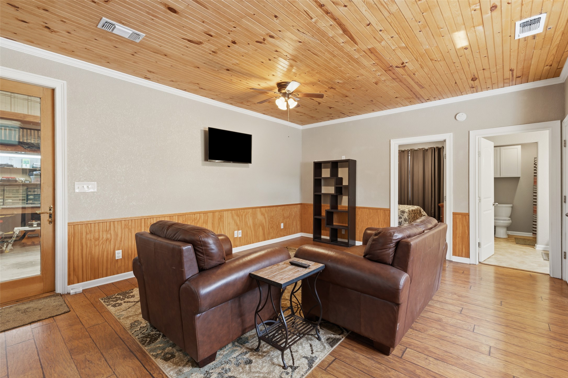764 Stubbs Road Johnson City, TX 78636 - Photo 10 of 29 Natural wood paneling graces the ceiling and wainscoting, complementing the warm hardwood flooring in this cozy living space.