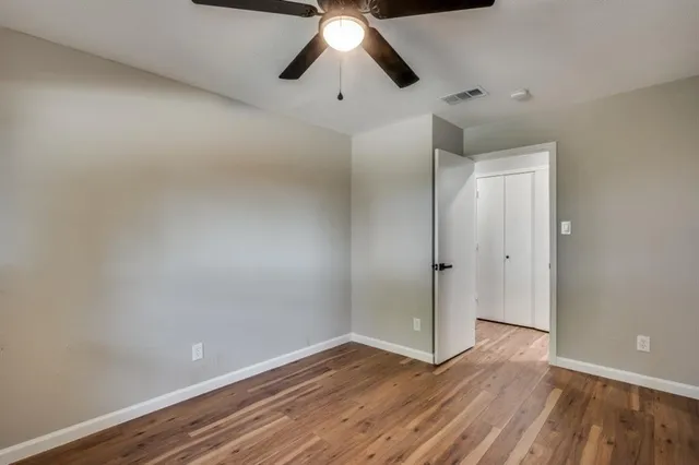a view of empty room with wooden floor and chandelier fan