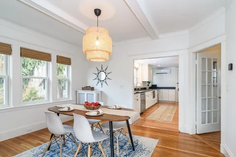 a dining room with wooden floor a chandelier a wooden table and chairs