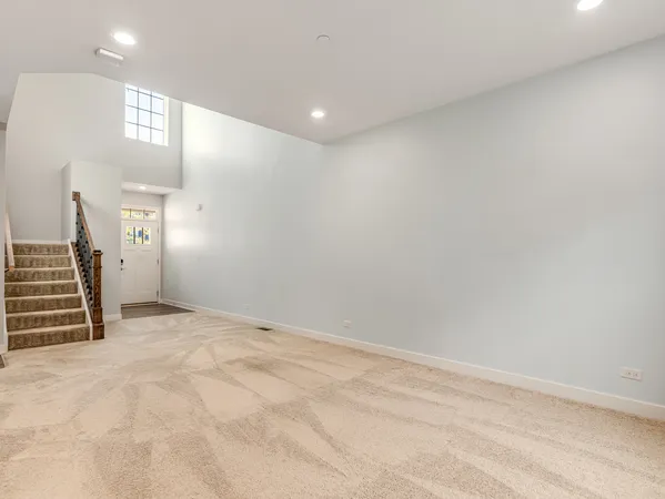 a view of an empty room with stairs and a kitchen