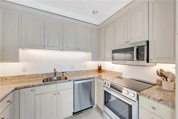 a kitchen with granite countertop white cabinets and white appliances