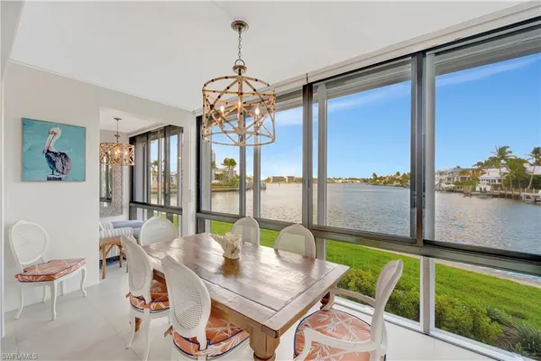 a view of a dining room with furniture a chandelier and large windows