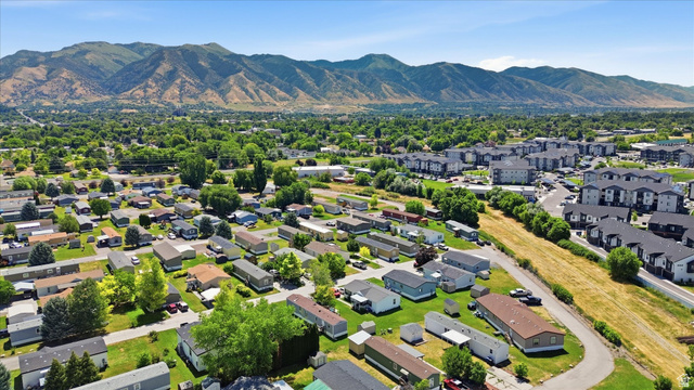 433 North 750 West Logan, UT 84321 - Photo 35 of 40 Aerial overview of a residential area with various housing types, verdant trees, and mountainous terrain in the background