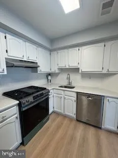 a kitchen with granite countertop white cabinets and stainless steel appliances