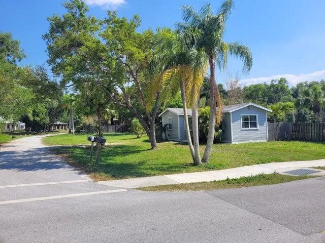 a view of a house with big yard and palm trees