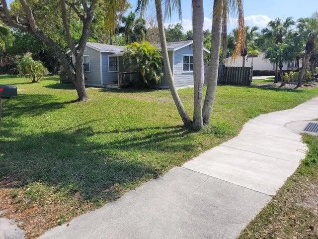 a view of a house with a yard and large trees