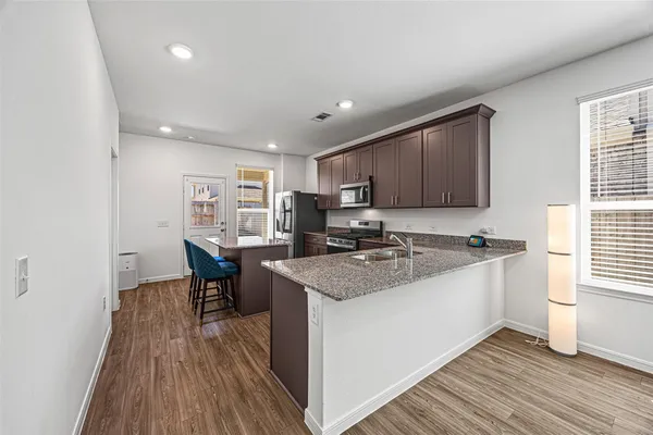 a kitchen with a sink appliances and wooden floor