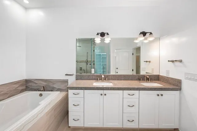 a bathroom with a granite countertop sink mirror and a bathtub