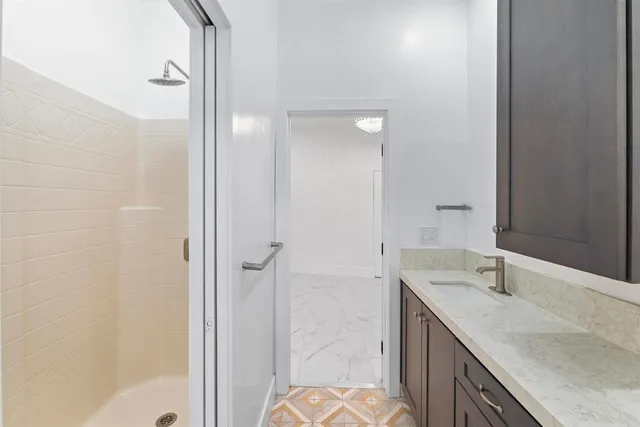 a bathroom with a granite countertop sink a mirror and a shower