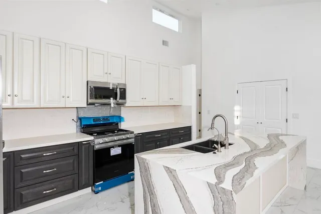 a kitchen with stainless steel appliances a sink a stove a microwave cabinets and a refrigerator