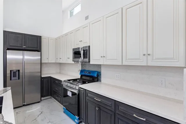 a kitchen with stainless steel appliances granite countertop a refrigerator a sink a stove and white cabinets