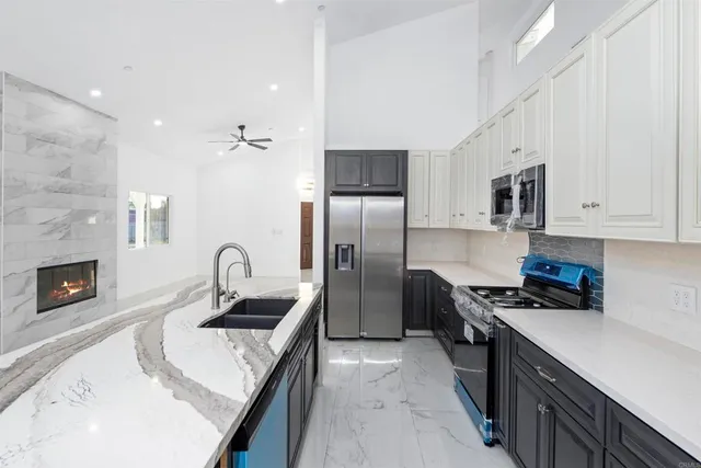 a kitchen with granite countertop a sink a counter top space stainless steel appliances and cabinets