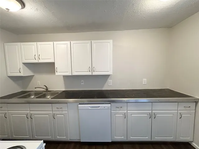 a kitchen with granite countertop white cabinets and a sink