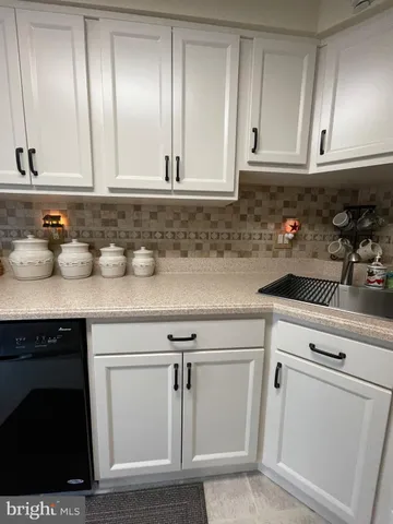 a kitchen with white cabinets and sink