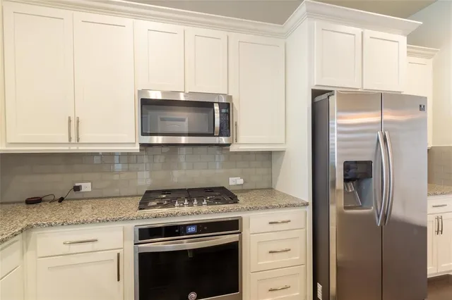 a kitchen with stainless steel appliances white cabinets and a stove a refrigerator with wooden floors