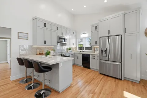 a kitchen with kitchen island granite countertop a stove a oven a sink a dining table and chairs