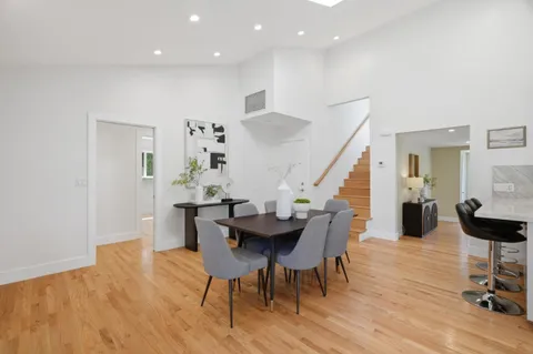 a kitchen with stainless steel appliances kitchen island granite countertop a refrigerator a stove a sink and white cabinets with wooden floor