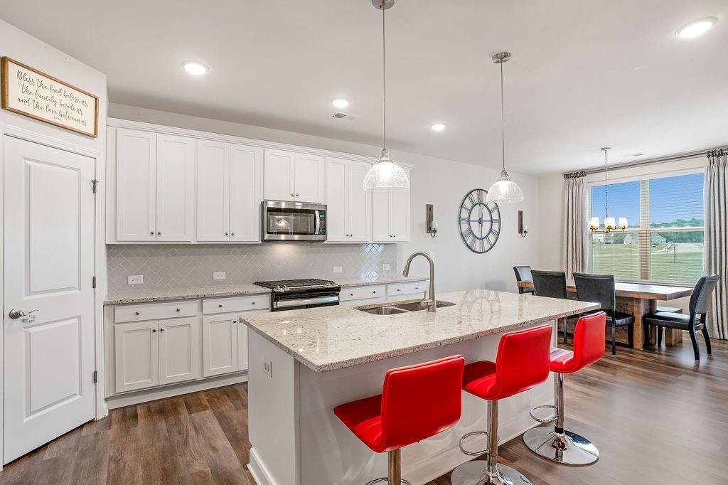 112 Leveret Road Locust Grove, GA 30248 - Photo 14 of 47 a kitchen with stainless steel appliances kitchen island granite countertop a stove a sink and white cabinets with wooden floor