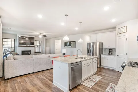 a open kitchen with stainless steel appliances kitchen island granite countertop a stove and a refrigerator