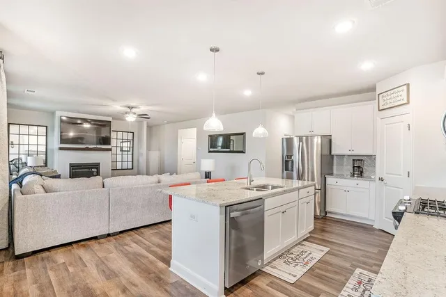 a open kitchen with stainless steel appliances kitchen island granite countertop a stove and a refrigerator