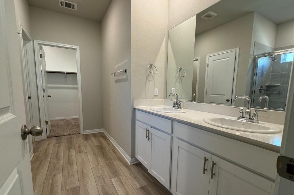 12604 Dairywork Road Buda, TX 78610 - Photo 8 of 20 Dual vanities and a spacious walk-in shower elevate this contemporary bathroom to a private oasis.
