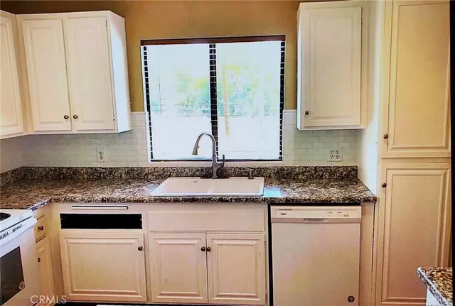 a kitchen with granite countertop white cabinets and a sink