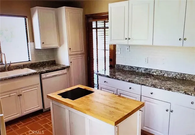 a kitchen with granite countertop a sink stove and cabinets