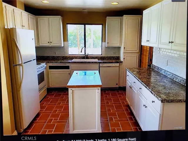 a kitchen with kitchen island granite countertop wooden cabinets a stove a sink and a refrigerator