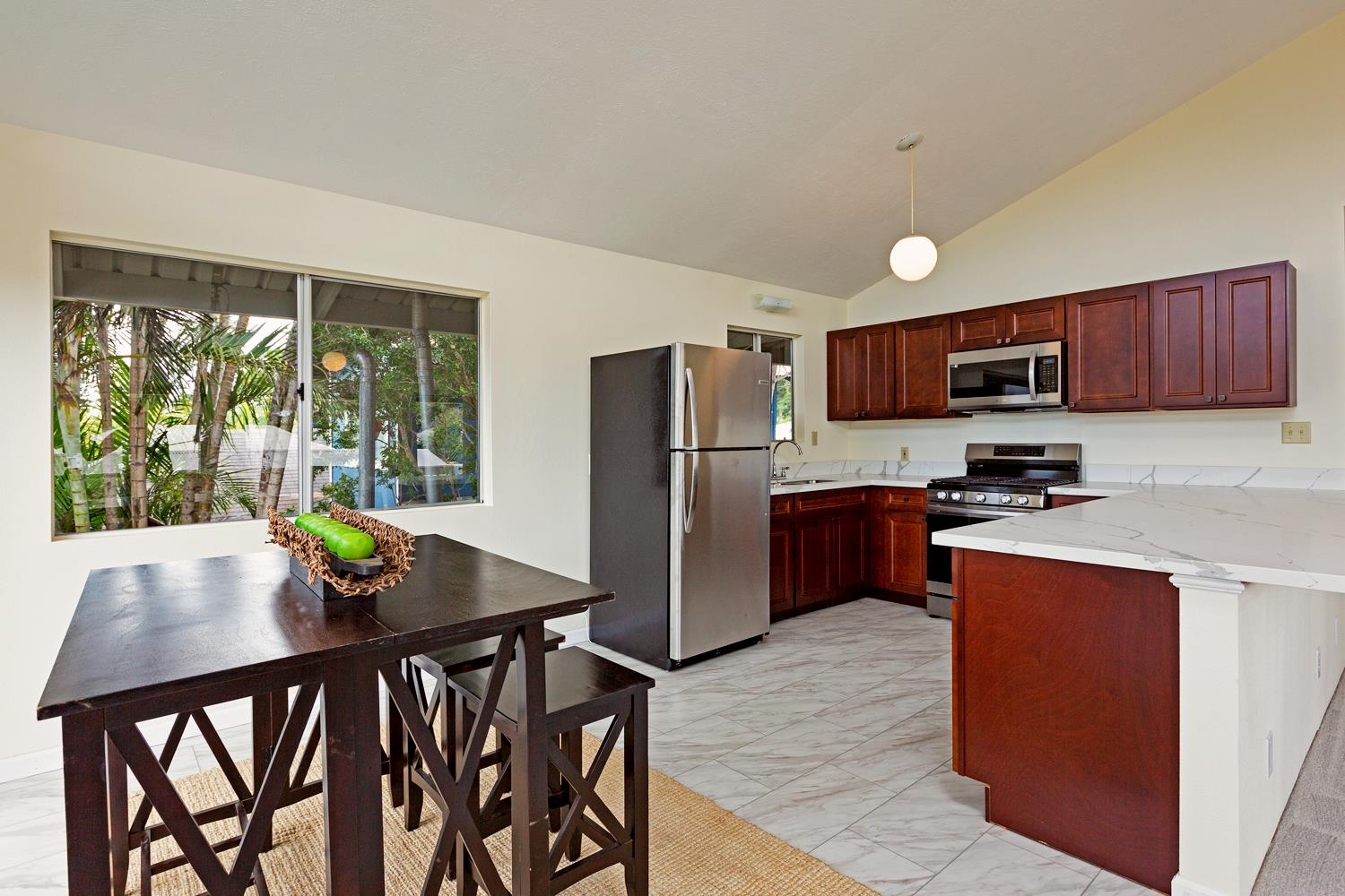 974 Haiku Road Haiku, HI 96708 - Photo 9 of 27 a kitchen with stainless steel appliances granite countertop a stove a refrigerator a sink a dining table and chairs with wooden floor