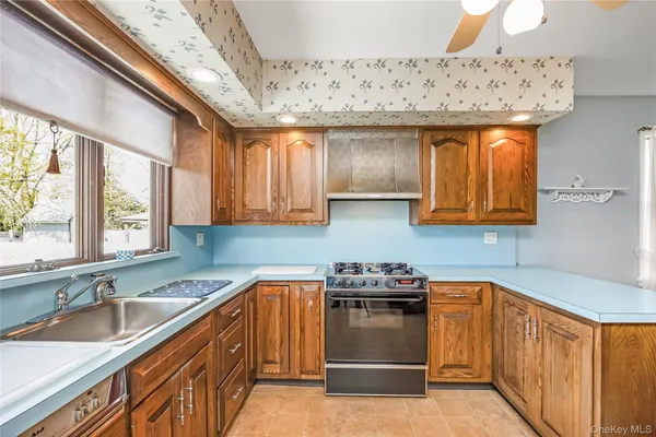 a kitchen with stainless steel appliances granite countertop a sink a stove and wooden cabinets
