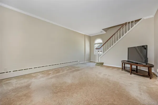 a view of an empty room with stairs and a window