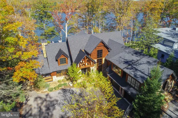 an aerial view of a house with swimming pool and large trees
