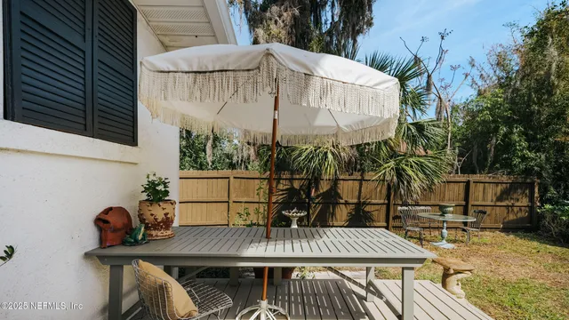 a view of a roof deck with table and chairs potted plants and large tree