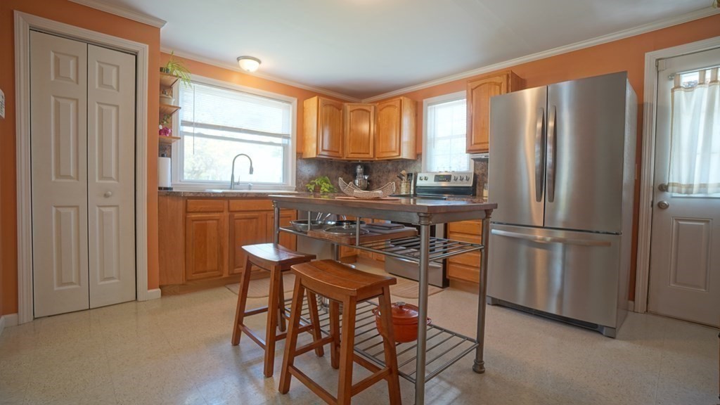 245 Fair Oak Road Springfield, MA 01128 - Photo 11 of 37 a kitchen with stainless steel appliances a refrigerator a stove a kitchen island and chairs in it