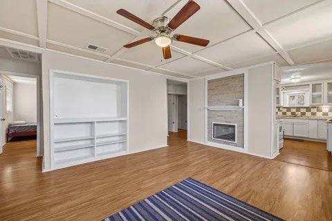 a view of an empty room with a fireplace and a ceiling fan